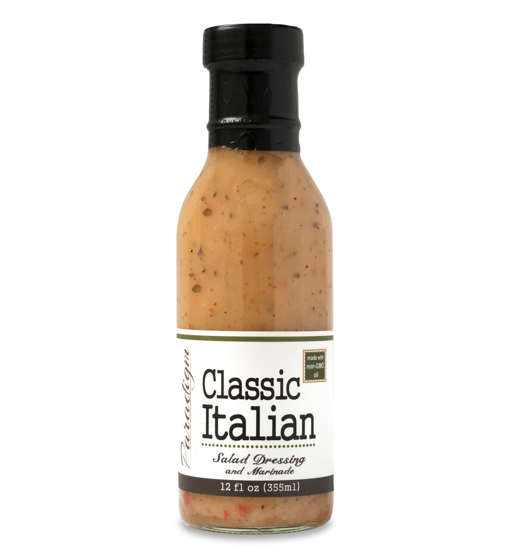 Glass ring neck bottle filled with Classic Italian dressing on white background. The bottle is labeled, “Paradigm Classic Italian Salad Dressing and Marinade – 12 fl oz (355ml)”.