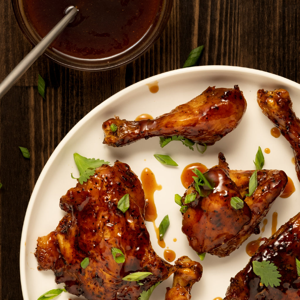chicken wings with paradigm foodworks teriyaki sauce on a white plate, served on a wooden table.