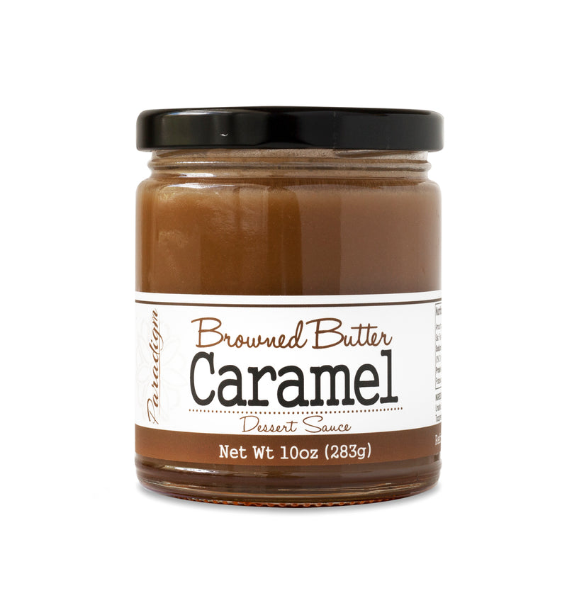 Short, lidded jar full of warm-colored caramel sauce, on white background. The jar is labeled “Paradigm Browned Butter Caramel Dessert Sauce – Net Weight 10oz (283g)”