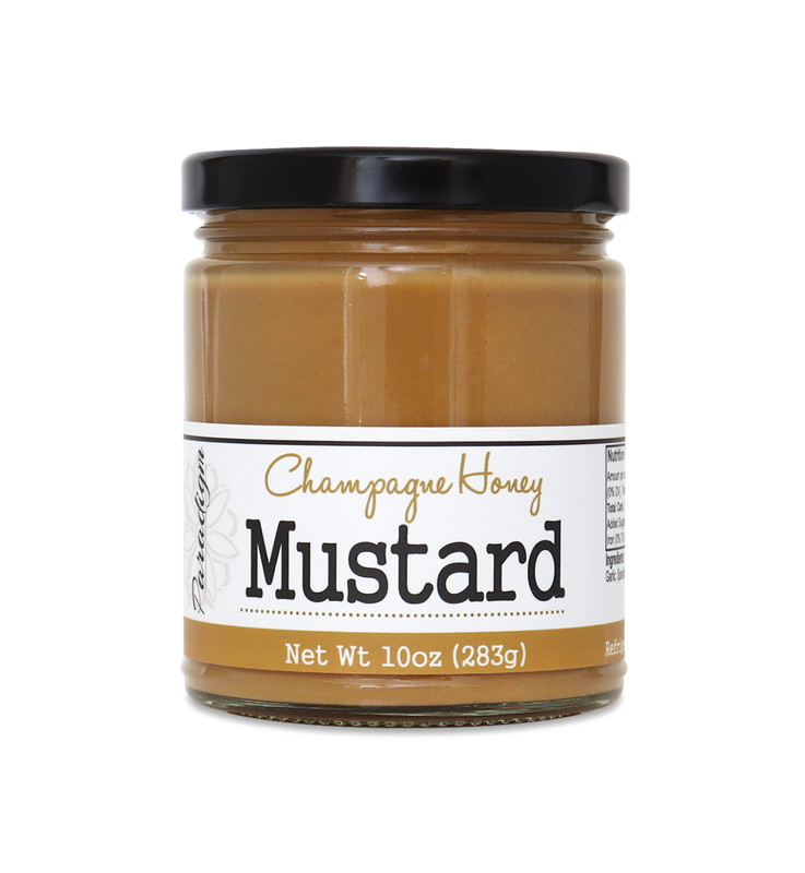 Short, lidded jar full of honey mustard on white background. The jar is labeled, “Paradigm Champagne Honey Mustard – Net Weight 10oz (283g)”