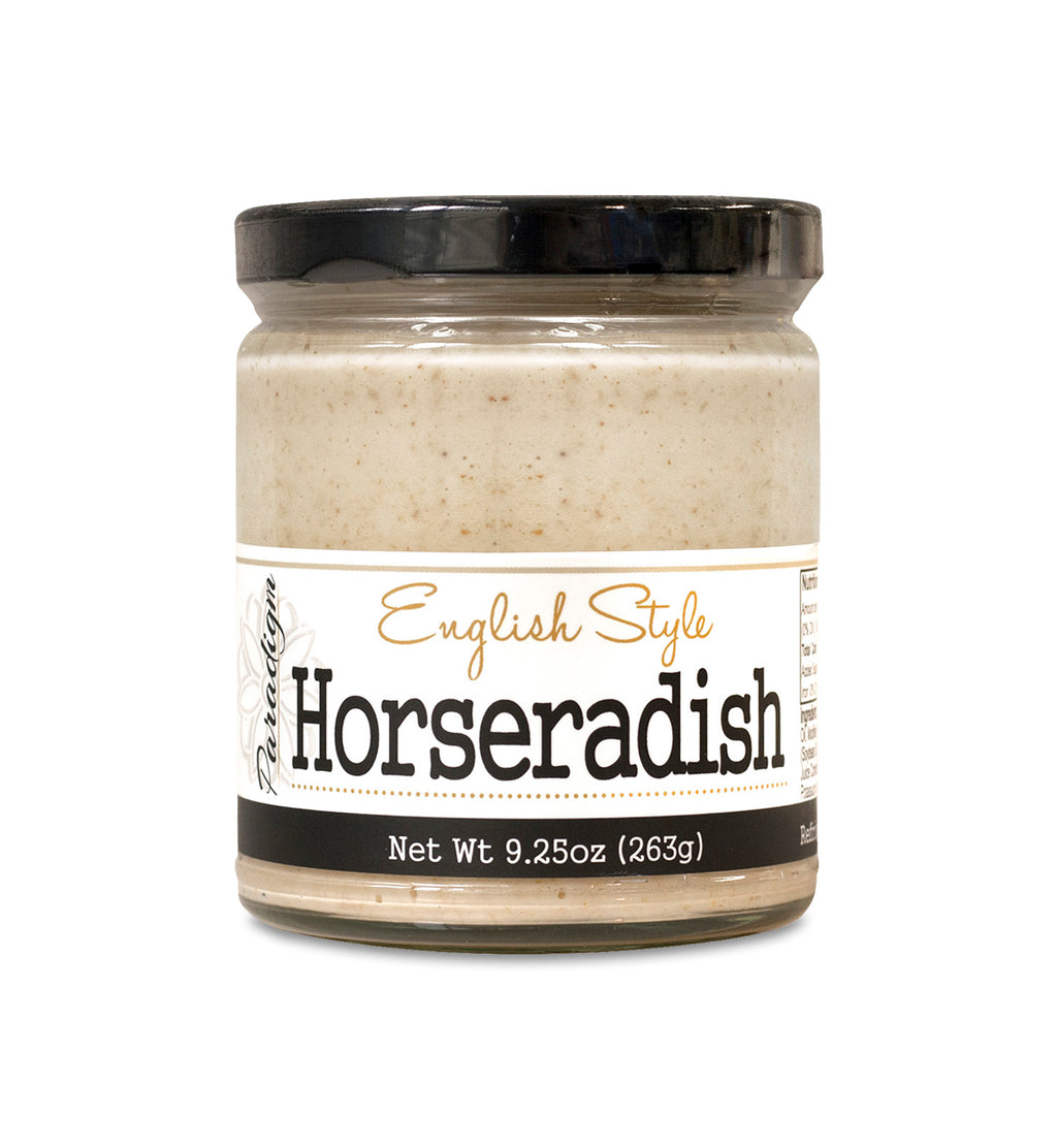 Short, lidded jar full of horseradish on white background. The jar is labeled, “Paradigm English Style Horseradish – Net Weight 9.25oz (263g)”.