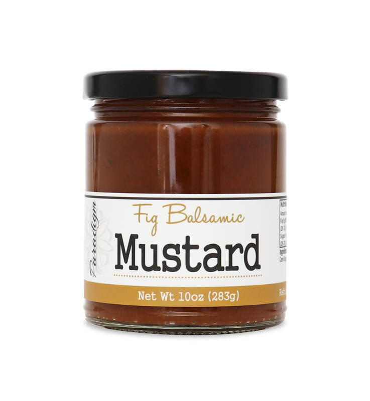 Short, lidded jar full of fig balsamic mustard on white background. The jar is labeled, “Paradigm Fig Balsamic Mustard Net Weight 10oz (283g)”. 