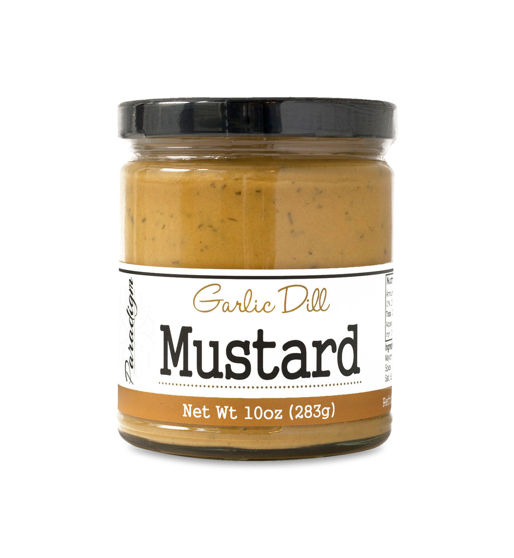 Short, lidded jar full of garlic dill mustard on white background. The jar is labeled, “Paradigm Garlic Dill Mustard – Net Weight 10oz (283g)”.