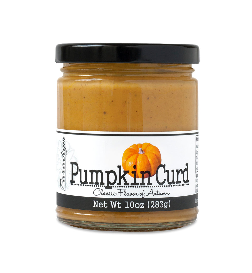 Short, lidded jar full of Pumpkin Curd, on white background. The jar is labeled “Paradigm Pumpkin Curd Classic Flavor of Autumn – Net Weight 10oz (283g)” 