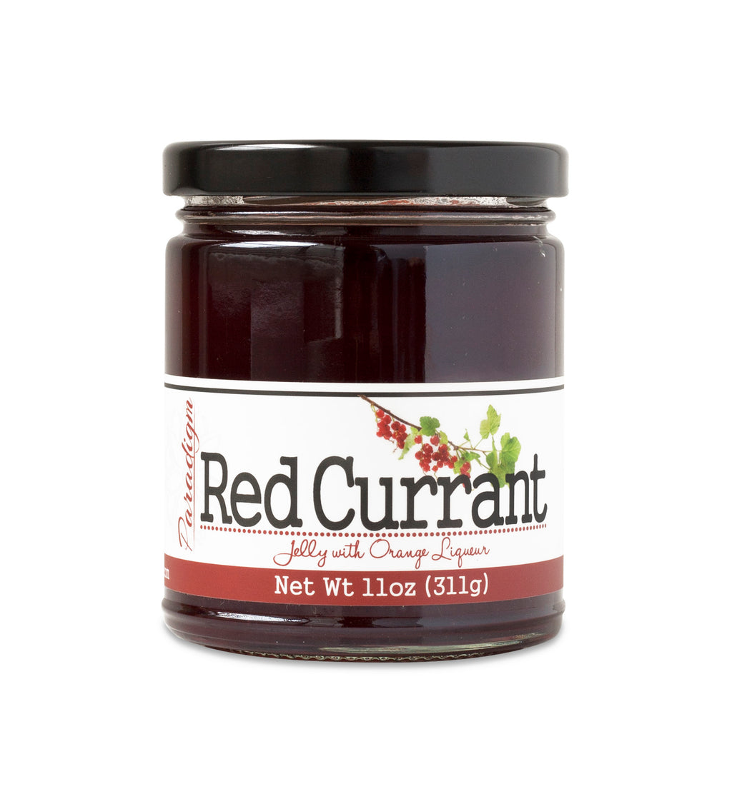 Short, lidded jar full of red currant jelly, on white background. The jar is labeled “Paradigm Red Currant Jelly with Orange Liqueur – Net Weight 11oz (311g)”