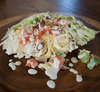 Cabbage wedge salad topped with diced tomatoes, green onions, and ranch on a woof surface