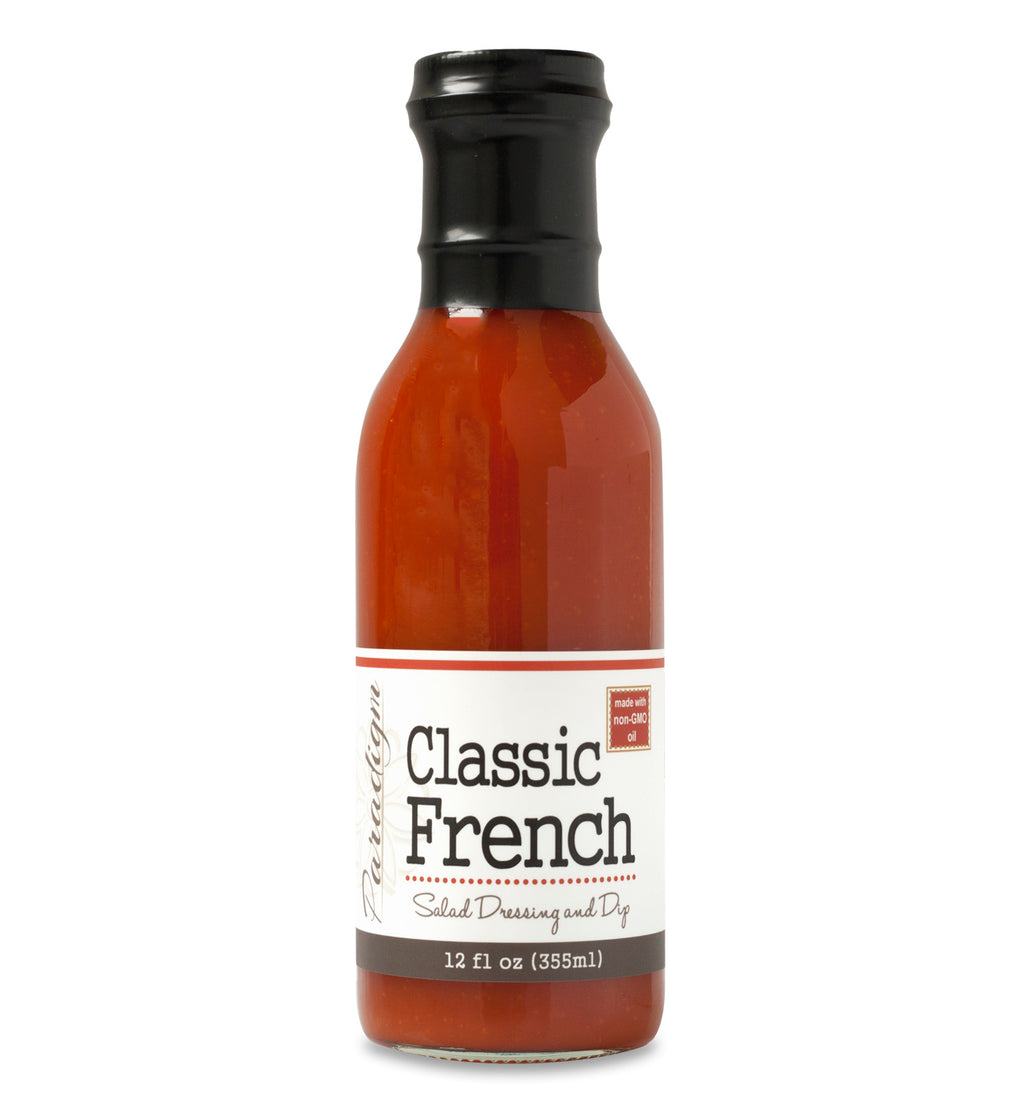 Glass ring neck bottle filled with french dressing on white background. The bottle is labeled, “Paradigm Classic French Salad Dressing and Dip – Net Weight 12 fl oz (355ml)” and “Made with non-GMO oil”. 