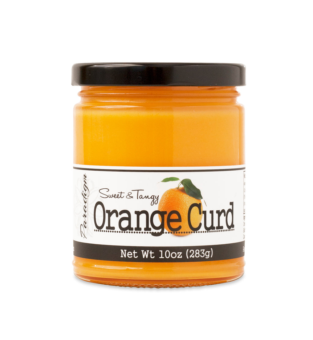 Short, lidded jar full of Orange Curd, on white background. The jar is labeled “Paradigm Sweet & Tangy Orange Curd– Net Weight 10oz (283g)” 