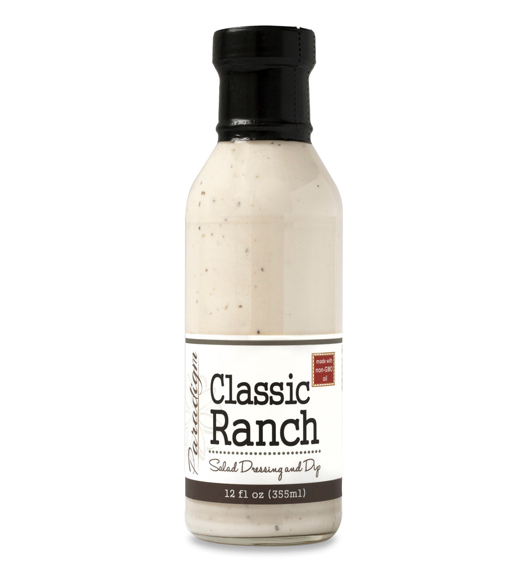 Glass ring neck bottle filled with ranch on white background. The bottle is labeled, “Paradigm Classic Ranch Salad Dressing and Dip – Net Weight 12 fl oz (355ml)” and “Made with non-GMO oil”. 
